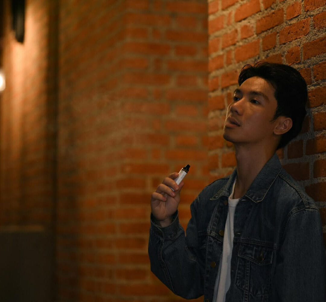 man-smoking-with-electronic-cigarette-standing-night-city-with-blurred-night-street-lights-background